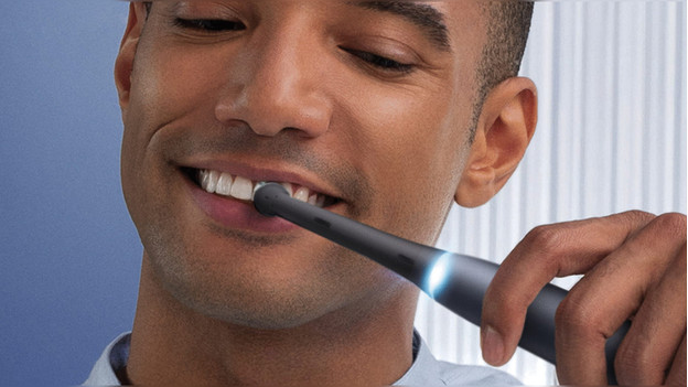 homme avec une brosse à dents électrique