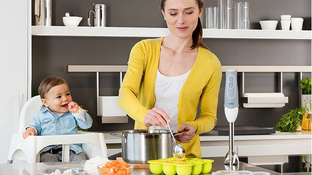 Mother prepares baby food for child