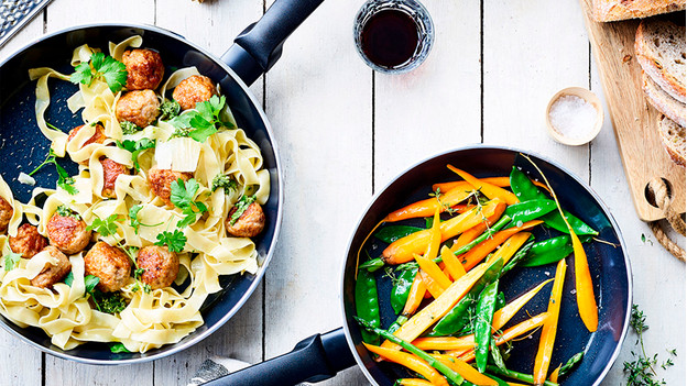 Poêle en céramique avec des pâtes, des boulettes de haché et des légumes