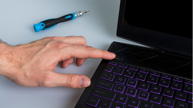 Turn off laptop. Next to the laptop is a screwdriver.