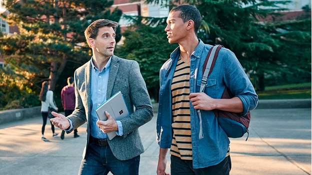 Un homme sort avec la Surface Pro sous le bras et parle à un autre homme.