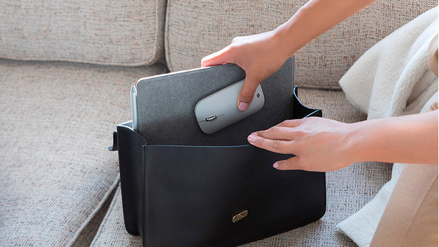 Femme qui met un petit PC portable dans son sac.