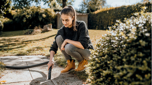 Une femme utilise un aspirateur de chantier dans le jardin
