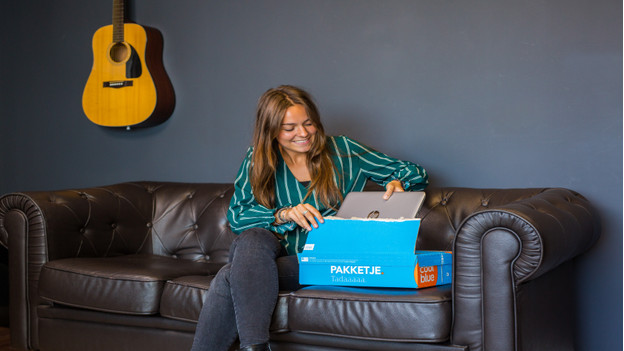 Une dame prend un PC portable Deuxième Chance dans une boite Coolblue