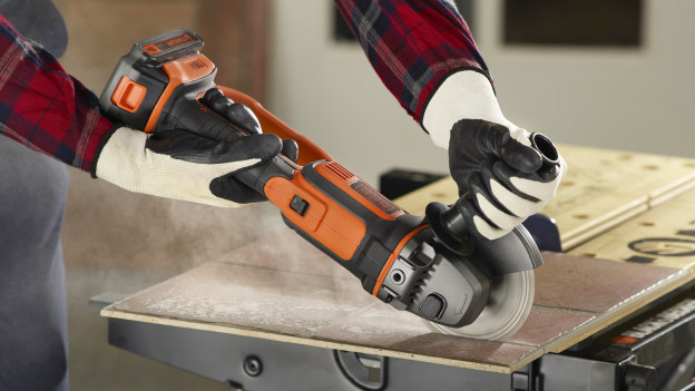 Un homme coupe du carrelage avec une meuleuse d'angle BLACK+DECKER