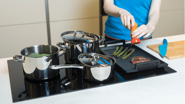 Casseroles avec couvercles sur une plaque de cuisson