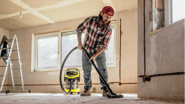 Un homme aspire la poussière de chantier avec un aspirateur de chantier