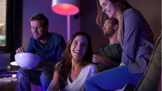 Mensen samen op bank met Philips Hue verlichting aan.