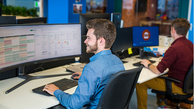 Un homme travaille sur un grand écran PC au bureau.