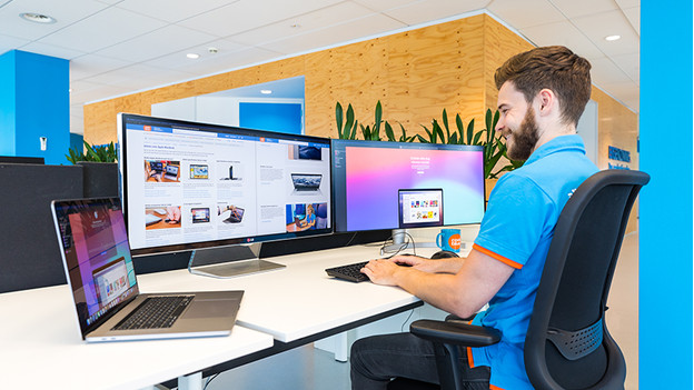 man werkt op 2 beeldschermen met macbook