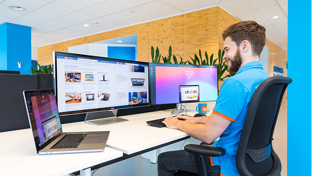 man works on 2 screens with MacBook