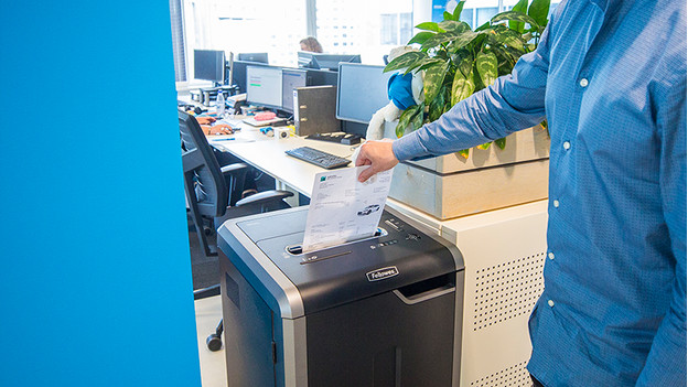 Un homme détruit un document dans le destructeur de papier.