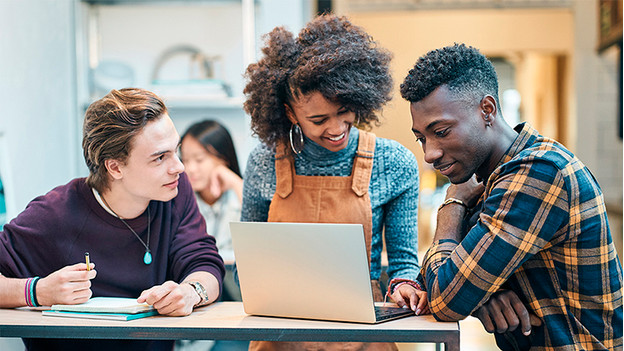 Trois étudiants travaillent ensemble derrière l'ordinateur portable.