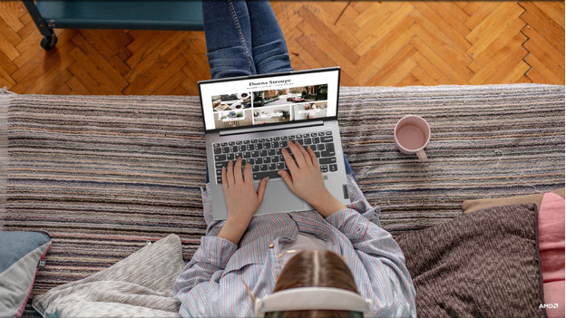 Iemand die op de bank zit en op een laptop werkt.