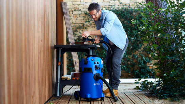 L'homme travaille avec des outils connectés à un aspirateur de chantier