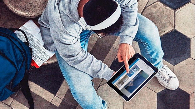 Un homme avec un casque audio utilise un ordinateur portable à écran tactile en mode tablette.