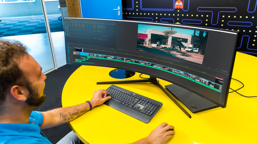 Spécialiste au travail dans Adobe Premiere Pro sur un écran PC 4K incurvé ultralarge
