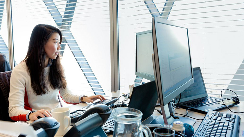 Une femme travaille derrière son PC au bureau.