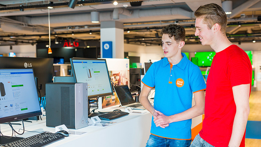Coolblue winkelmedewerker adviseert klant in winkel met voetbal op de achtergrond.