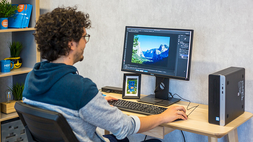Specialist bewerkt foto's in Adobe Photoshop met een zakelijke desktop