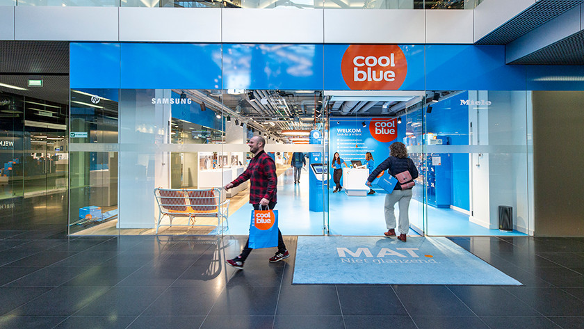 Un homme sort d'un magasin Coolblue avec un sac Coolblue en main.