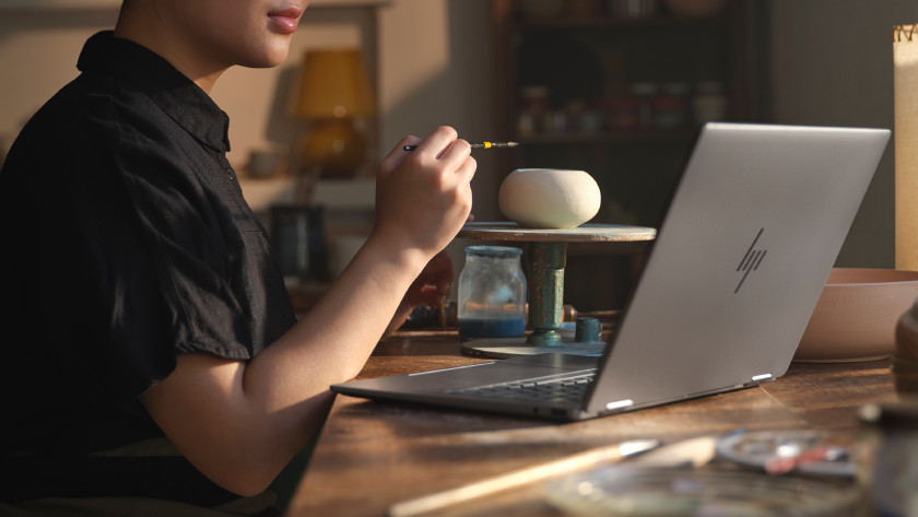 Vrouw die een pot beschildert met een HP Envy laptop voor haar