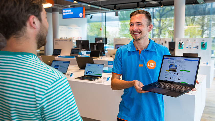 Coolblue medewerker toont laptop in winkel aan klant. 