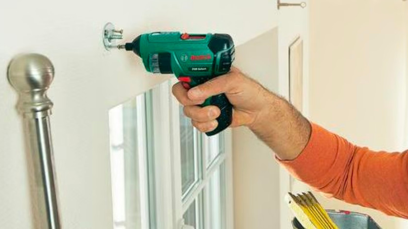 Tighten screw in wall with Bosch electric screwdriver