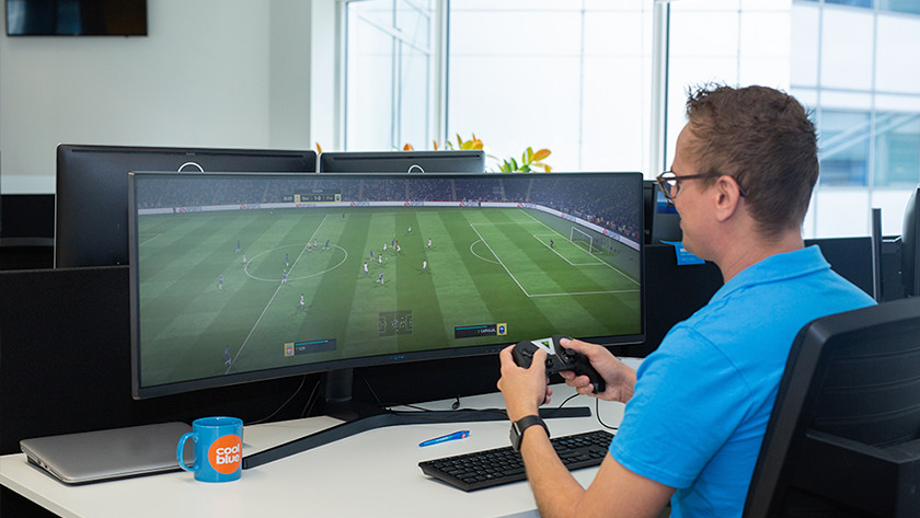 Un homme joue à FIFA sur un écran PC ultralarge pour le gaming sur console