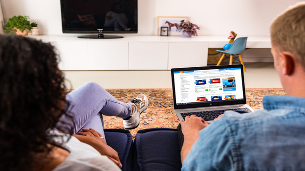 Assise sur un banc en cherchant un PC portable Deuxième Chance sur le site Coolblue