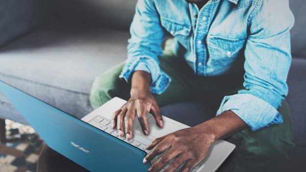Man sits on couch and works on laptop