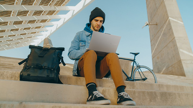 Une fille tape sur un PC portable. Un téléphone est sur la table.