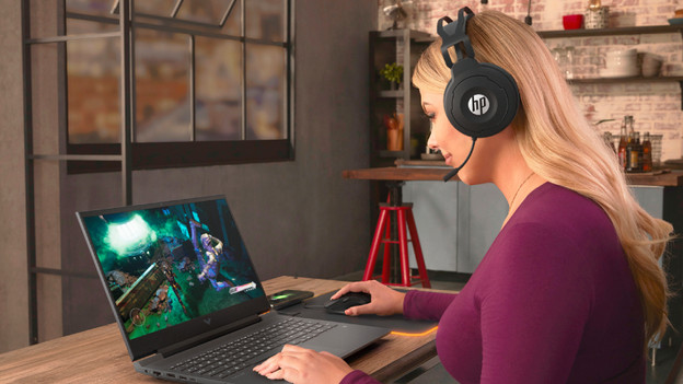 Person is working on a 17-inch laptop with various accessories on her desk.