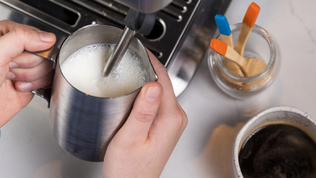 buse vapeur dans pichet rempli de lait