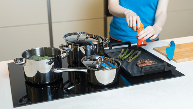 Casseroles avec couvercles sur une plaque de cuisson