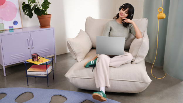 Une femme travaille sur un PC portable 15 pouces avec une tasse à café à côté.