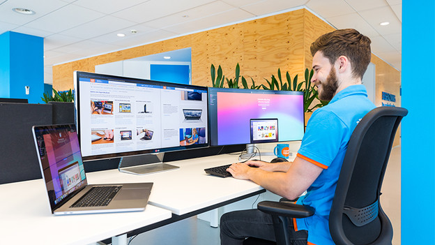 un homme travaille sur son MacBook avec deux écrans