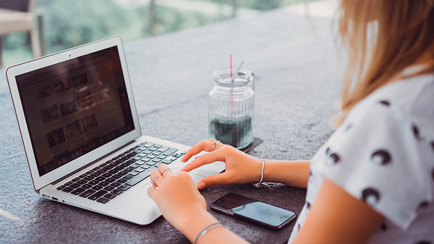 Person's typing on laptop. A phone is on the table.