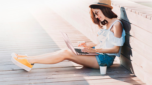 A person with a hat uses an ASUS laptop and drinks coffee