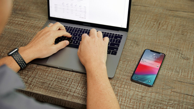 Typing on laptop with iPhone next to it