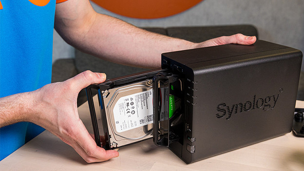 Man plaatst Seagate harde schijf in Synology NAS. 