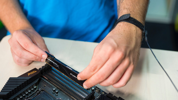 Expert uses an antistatic wrist strap to place RAM on a motherboard
